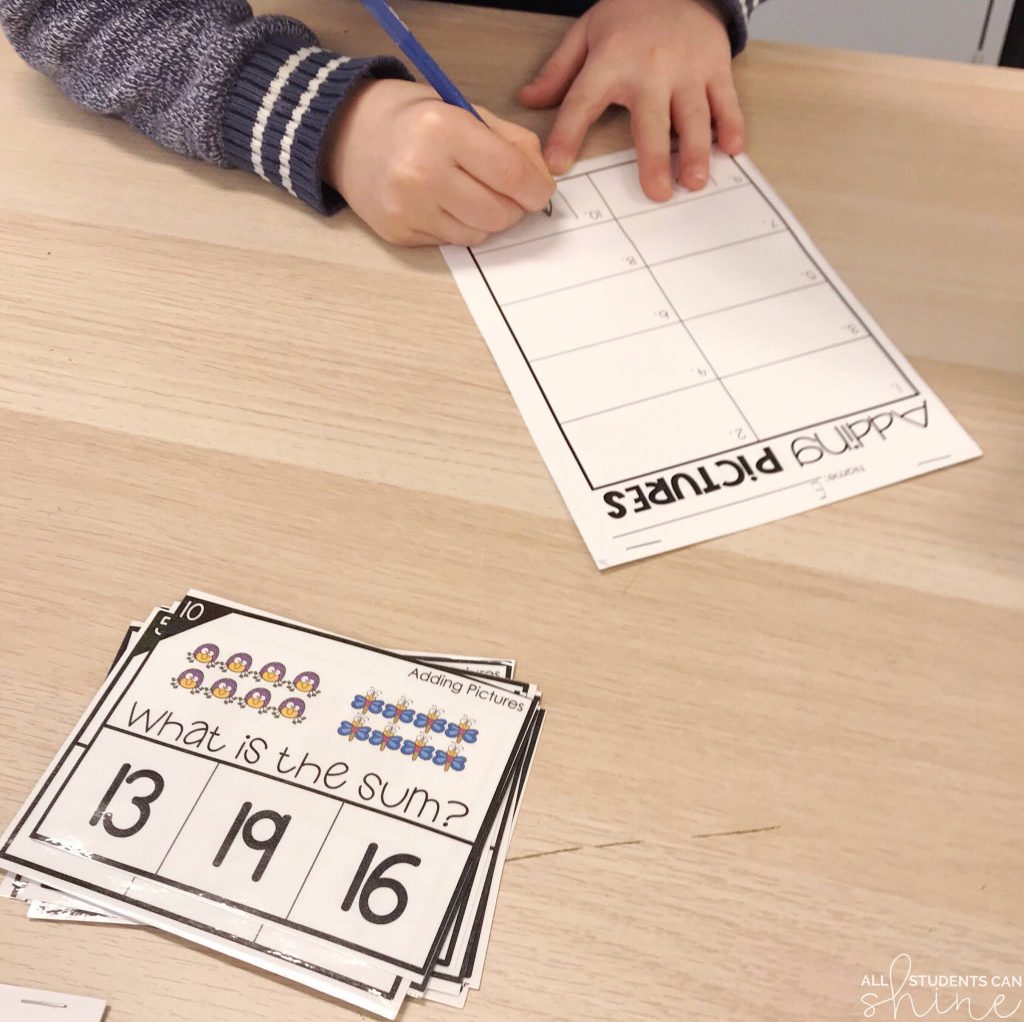 math centers addition pictures activity with task cards and student writing answers on worksheet